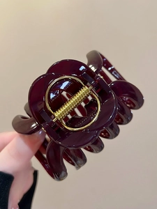 Detailed close-up of large burgundy acrylic hair claw clip with golden metal spring