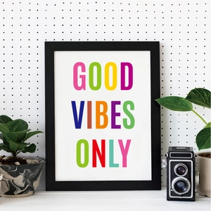 Close-up of colorful GOOD VIBES ONLY wall art print with a black frame on a white pegboard