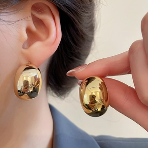 Macro shot of large polished gold waterdrop earrings showing metallic texture and scale