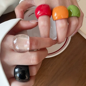 Detailed view of colorful resin rings in red, orange, and green on a model hand