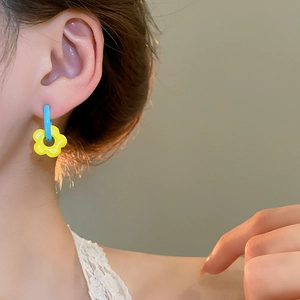 Close-up of asymmetrical flower drop earrings with blue and yellow paint finish