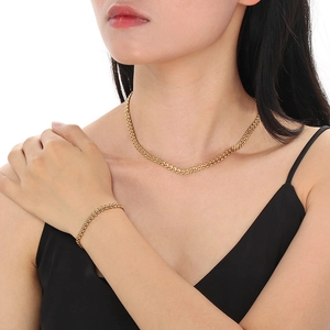 Detail of golden wheat link chain necklace and bracelet set on a female model