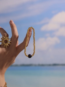 Close-up of 18k gold-plated beaded bracelet and sun ring on woman at the beach