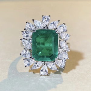 Macro shot of S925 silver ring featuring emerald cut center stone with pear-shaped halo
