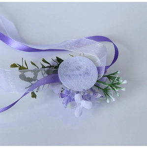 Macro view of purple wrist corsage showing handmade base structure and satin ribbons