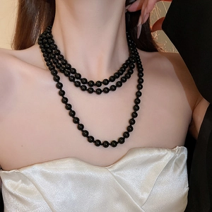Detailed view of elegant triple-layer black faux pearl necklace with glossy finish