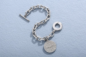Silver chain bracelet detail with T-bar clasp and vintage round coin medallion charm