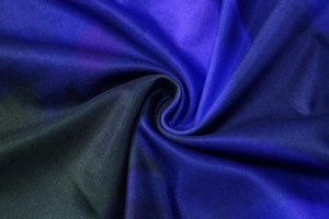 Dettaglio macro del tessuto con stampa floreale blu scuro e viola a trama elastica