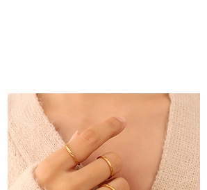 Close-up of 18K gold-plated C-shaped knot ring worn over a cozy beige knit sweater