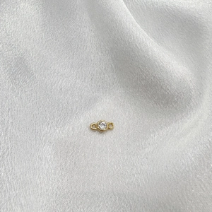 Macro shot of S925 sterling silver connector with sparkling zircon on white silk fabric