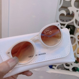 Close-up of children's ivory round sunglasses and branded faux leather storage case