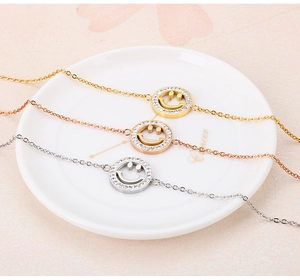 Drei Smiley-Armbänder in Gold, Roségold und Silber auf einer weißen Schale im Detail