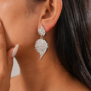 Detail showing metallic textured drop earrings worn on ear with wrinkled silver finish