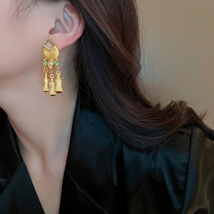 Detailed view of vintage gold tassel earrings with pearls on model in warm light