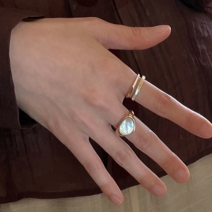 Close-up of golden ring set featuring mother of pearl stone and multilayered bands