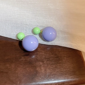 Detail of minimalist double ball earrings featuring purple and light green contrast finish