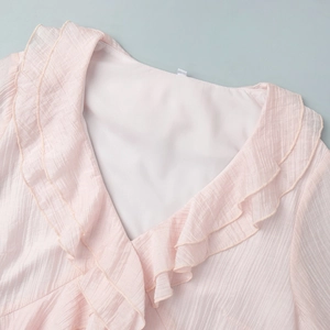 Close-up of elegant V-neckline with layered ruffle details on light pink chiffon dress