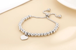 Macro shot of silver beaded bracelet featuring a heart pendant and adjustable sliding clasp