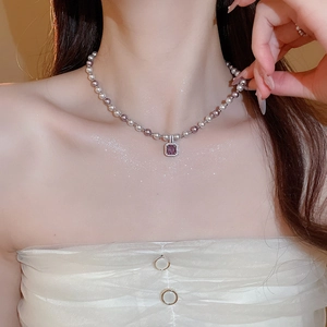 Detail of zircon manta rose pearl necklace with a purple gemstone pendant on a model