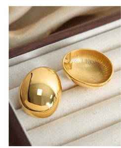 Macro detail of gold snail shell earrings showing radiant textured inner engraving