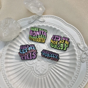 Set of four colorful enamel pins with English quotes on a white ceramic plate