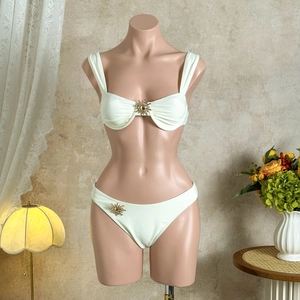 Détail d'un bikini blanc avec des ornements de soleil dorés et un tissu plissé