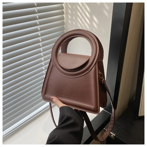 Detail of vintage brown trapezoid handbag featuring unique circular cutout handle and leather
