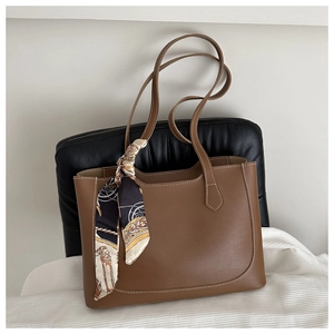 Gros plan détaillé d'un sac cabas marron en cuir avec un foulard décoratif en soie