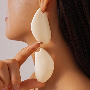 Gros plan d'un mannequin portant de grandes boucles d'oreilles en résine crème mat