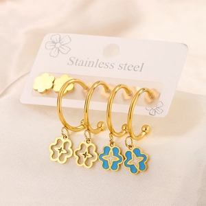 Close-up of gold stainless steel earrings set with blue enamel flower charms on card