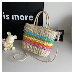 Detail of colorful rainbow stripes on a woven straw bag with handles and strap