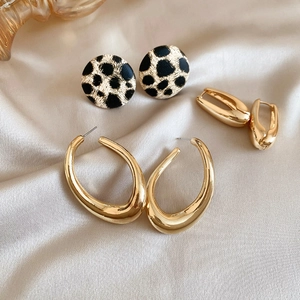 Detail view of gold earrings set featuring leopard print studs and polished metal hoops