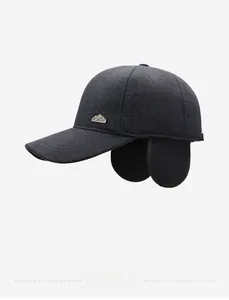 Detail of winter baseball cap with ear flaps featuring a metal mountain logo and fabric texture