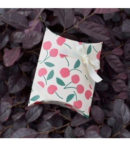 Mini pillow gift box featuring red cherry prints and an elegant cream ribbon bow detail