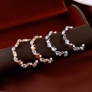 Macro shot of star-shaped zircon C-shaped earrings in polished gold and silver finishes