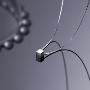 Detailed view of 3D cube pendant on fine box chain with elegant mirror reflection