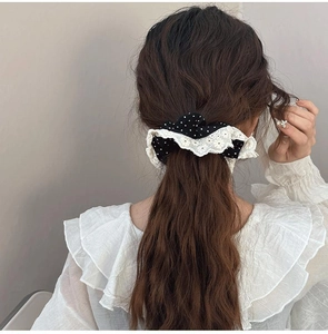 Detail of vintage polka dot scrunchie with lace trim styled on wavy brunette hair