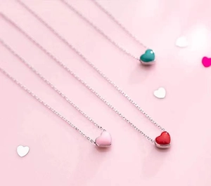 Close-up of colorful heart enamel pendants in pink, red, and blue on silver chains