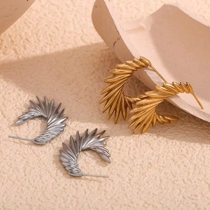 Modern geometric wing stud earrings in gold and silver finish on textured background