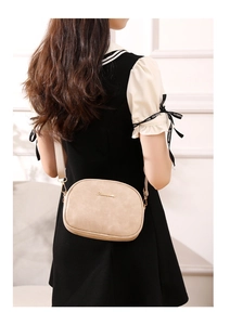 Oatmeal wax leather camera bag detail featuring gold logo and woven wide shoulder strap