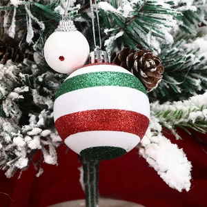Close-up of red and green glitter striped Christmas ball and white polka dot ornament