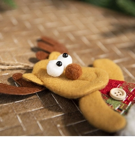 Detail of yellow felt Christmas reindeer ornament with brown antlers and plaid fabric