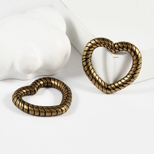Vintage gold heart earrings with spiral woven texture shown on white background props