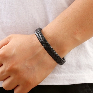 Handwoven black leather bracelet with stainless steel clasp worn on a model's wrist