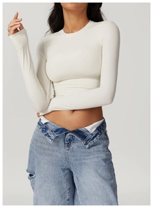 Close-up of tight white long-sleeve yoga top paired with ripped denim jeans