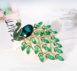 Close-up of green crystal peacock brooch with gold-tone alloy base and emerald stones