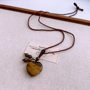 Macro view of heart-shaped tiger eye pendant with hand-woven brown rope details