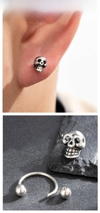 Detailed macro view of vintage stainless steel skull earrings with a distressed finish