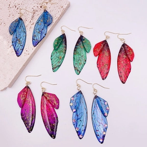 Macro view of iridescent cicada wing earrings in blue green and red with gold foil