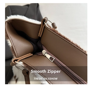 Detailed close-up of the smooth metal zipper and plush fur trim on the brown tote bag